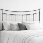 Cabecero de forja negro con diseño curvo y barrotes verticales en dormitorio minimalista