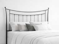 Cabecero de forja negro con diseño curvo y barrotes verticales en dormitorio minimalista